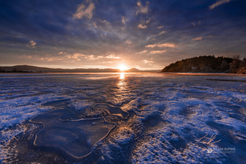 Sončni vzhod nad zaledenelim Cerkniškim jezerom.