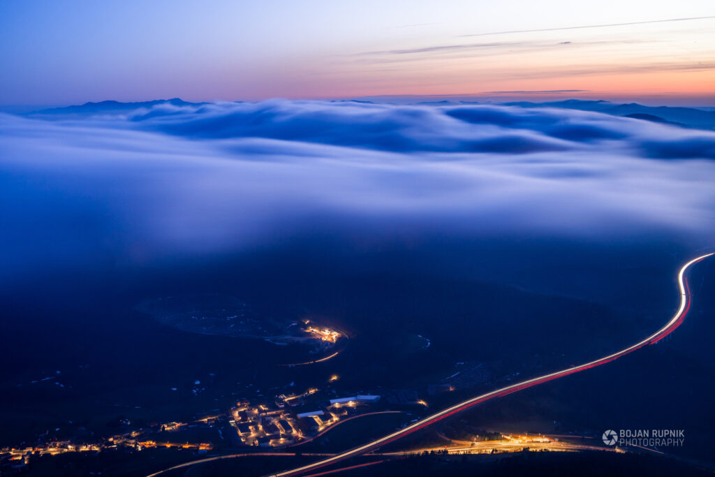 Večerni pogled z gore v zamegljeno dolino in sončnim zahodom